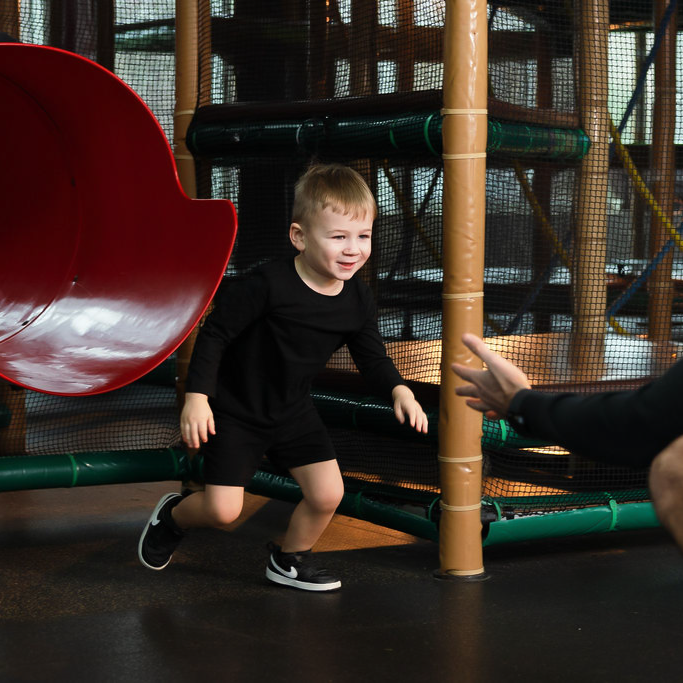 boy running into dad's arms after slide